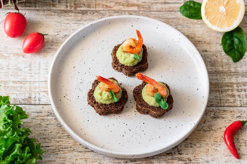 Canapes with avocado muslim and garlic shrimp on brown bread. Simple and easy snack for parties and banquets. Comfortable food. Canapes with avocado muslim and garlic shrimp on brown bread. Simple and easy snack for parties and banquets. Comfortable food