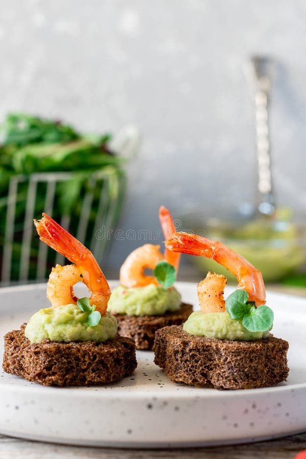 Canapes with avocado muslim and garlic shrimp on brown bread. Simple and easy snack for parties and banquets. Comfortable food. Canapes with avocado muslim and garlic shrimp on brown bread. Simple and easy snack for parties and banquets. Comfortable food