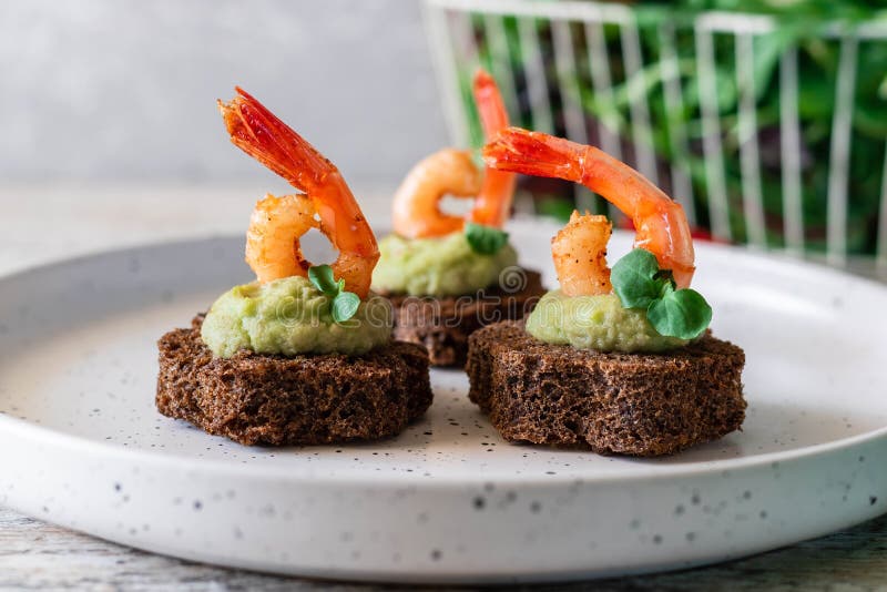 Canapes with avocado muslim and garlic shrimp on brown bread. Simple and easy snack for parties and banquets. Comfortable food. Canapes with avocado muslim and garlic shrimp on brown bread. Simple and easy snack for parties and banquets. Comfortable food