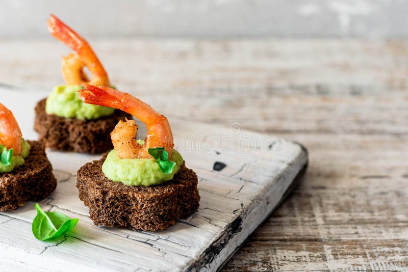 Canapes with avocado muslim and garlic shrimp on brown bread. Simple and easy snack for parties and banquets. Comfortable food. Canapes with avocado muslim and garlic shrimp on brown bread. Simple and easy snack for parties and banquets. Comfortable food