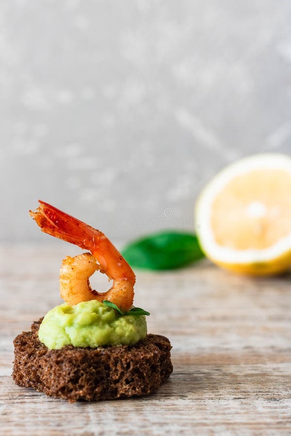 Canapes with avocado muslim and garlic shrimp on brown bread. Simple and easy snack for parties and banquets. Comfortable food. Canapes with avocado muslim and garlic shrimp on brown bread. Simple and easy snack for parties and banquets. Comfortable food