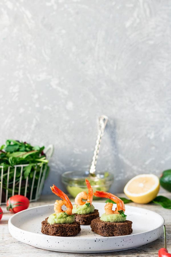 Canapes with avocado muslim and garlic shrimp on brown bread. Simple and easy snack for parties and banquets. Comfortable food. Canapes with avocado muslim and garlic shrimp on brown bread. Simple and easy snack for parties and banquets. Comfortable food