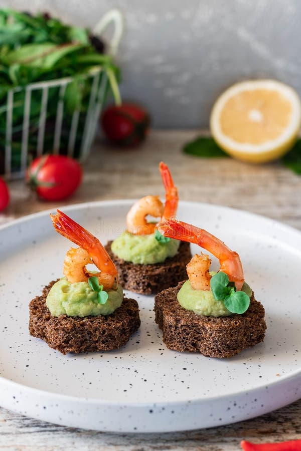 Canapes with avocado muslim and garlic shrimp on brown bread. Simple and easy snack for parties and banquets. Comfortable food. Canapes with avocado muslim and garlic shrimp on brown bread. Simple and easy snack for parties and banquets. Comfortable food