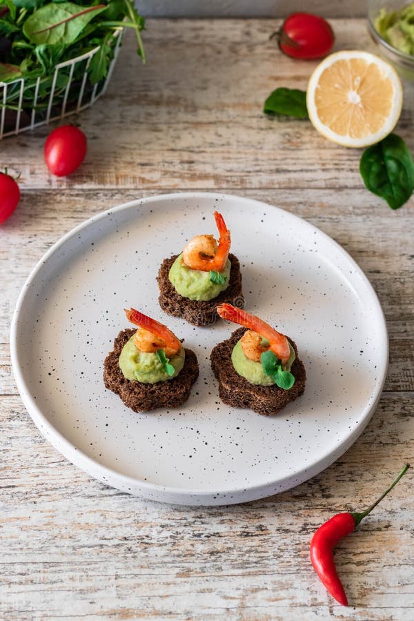 Canapes with avocado muslim and garlic shrimp on brown bread. Simple and easy snack for parties and banquets. Comfortable food. Canapes with avocado muslim and garlic shrimp on brown bread. Simple and easy snack for parties and banquets. Comfortable food