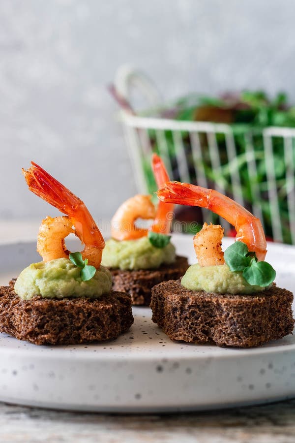 Canapes with avocado muslim and garlic shrimp on brown bread. Simple and easy snack for parties and banquets. Comfortable food. Canapes with avocado muslim and garlic shrimp on brown bread. Simple and easy snack for parties and banquets. Comfortable food