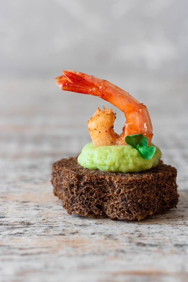 Canapes with avocado muslim and garlic shrimp on brown bread. Simple and easy snack for parties and banquets. Comfortable food. Canapes with avocado muslim and garlic shrimp on brown bread. Simple and easy snack for parties and banquets. Comfortable food