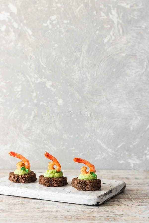 Canapes with avocado muslim and garlic shrimp on brown bread. Simple and easy snack for parties and banquets. Comfortable food. Canapes with avocado muslim and garlic shrimp on brown bread. Simple and easy snack for parties and banquets. Comfortable food