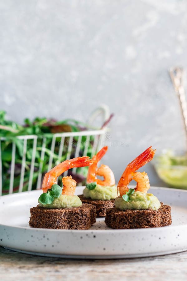 Canapes with avocado muslim and garlic shrimp on brown bread. Simple and easy snack for parties and banquets. Comfortable food. Canapes with avocado muslim and garlic shrimp on brown bread. Simple and easy snack for parties and banquets. Comfortable food