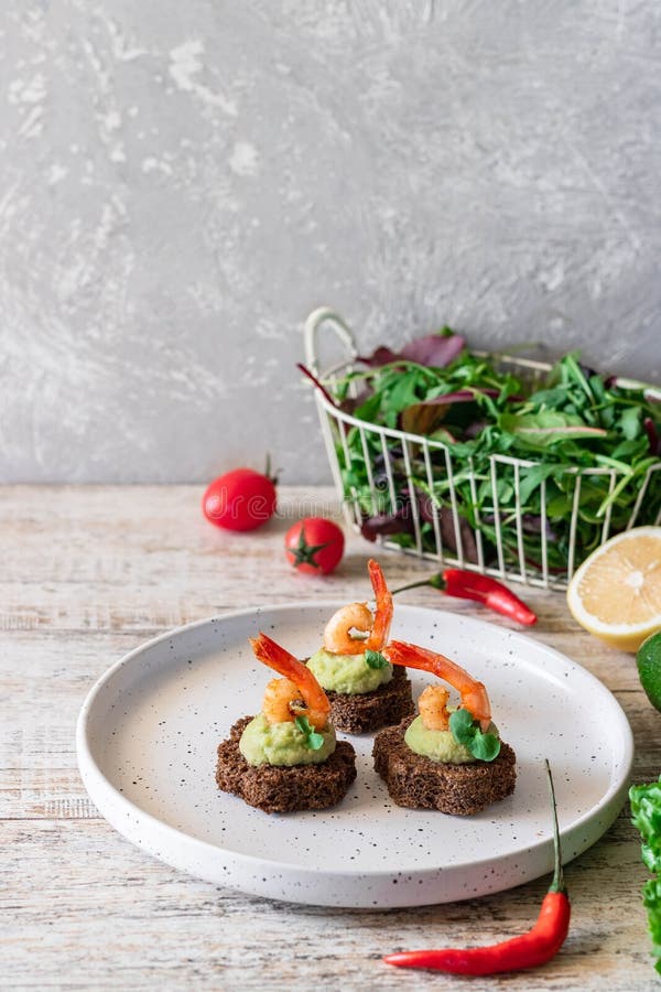 Canapes with avocado muslim and garlic shrimp on brown bread. Simple and easy snack for parties and banquets. Comfortable food. Canapes with avocado muslim and garlic shrimp on brown bread. Simple and easy snack for parties and banquets. Comfortable food