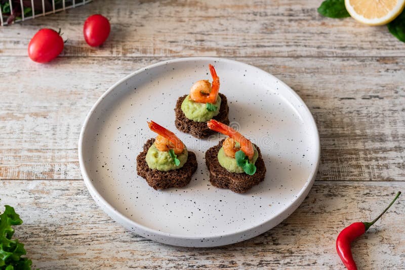 Canapes with avocado muslim and garlic shrimp on brown bread. Simple and easy snack for parties and banquets. Comfortable food. Canapes with avocado muslim and garlic shrimp on brown bread. Simple and easy snack for parties and banquets. Comfortable food