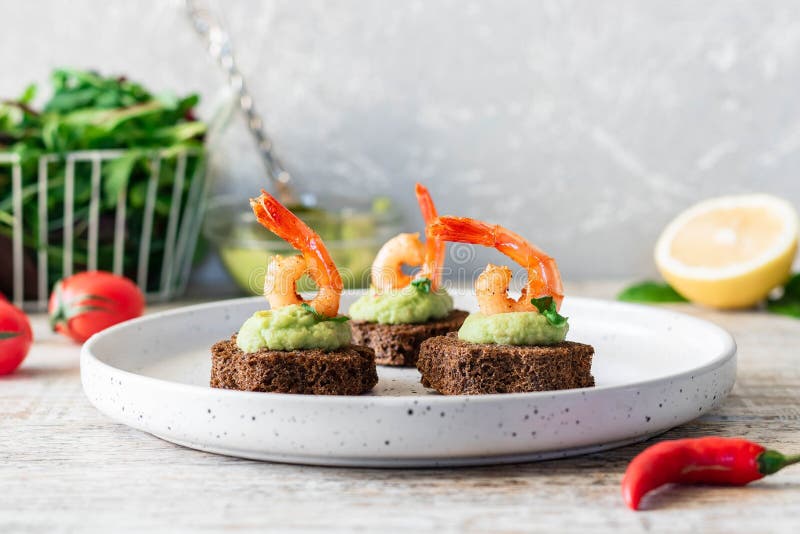 Canapes with avocado muslim and garlic shrimp on brown bread. Simple and easy snack for parties and banquets. Comfortable food. Canapes with avocado muslim and garlic shrimp on brown bread. Simple and easy snack for parties and banquets. Comfortable food