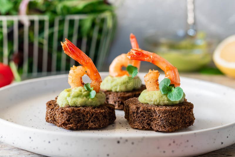 Canapes with avocado muslim and garlic shrimp on brown bread. Simple and easy snack for parties and banquets. Comfortable food. Canapes with avocado muslim and garlic shrimp on brown bread. Simple and easy snack for parties and banquets. Comfortable food