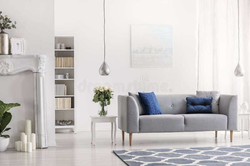 Canapé gris avec les coussins bleus dans l'intérieur élégant blanc de salon avec les fleurs et la peinture Photo réelle photographie stock libre de droits Canapé gris avec les coussins bleus dans l'intérieur élégant blanc de salon avec les fleurs et la peinture Photo réelle photographie stock libre de droits