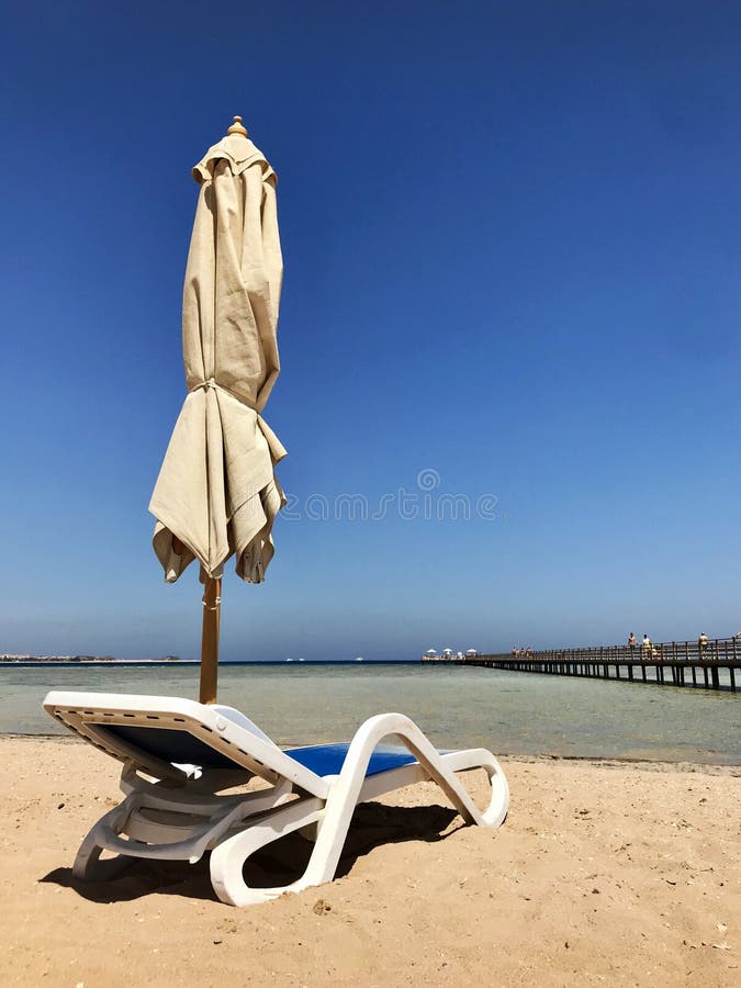 Canapé élégant dans à sable jaune pour exposer au soleil le lit pliant sur la plage en été sous le ciel ouvert photo libre de droits Canapé élégant dans à sable jaune pour exposer au soleil le lit pliant sur la plage en été sous le ciel ouvert photo libre de droits