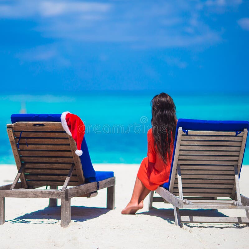 Canapés de plage avec Santa Hat et la jeune femme rouges photos stock Canapés de plage avec Santa Hat et la jeune femme rouges photos stock