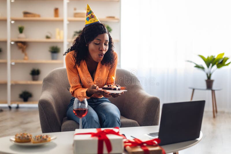Candela nera che soffia una torta e fa il suo compleanno online al chiuso immagini stock libere da diritti