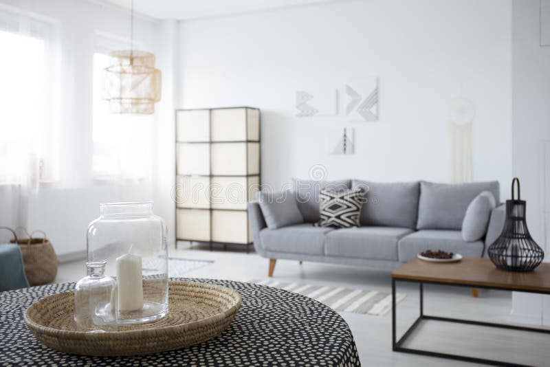 Candela sulla tavola nell'interno bianco spazioso del salone con il cuscino modellato sullo strato grigio Foto reale fotografia stock