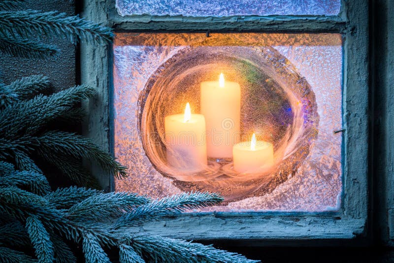 Candele brucianti per il Natale in finestra congelata alla vigilia fotografia stock libera da diritti Candele brucianti per il Natale in finestra congelata alla vigilia fotografia stock libera da diritti