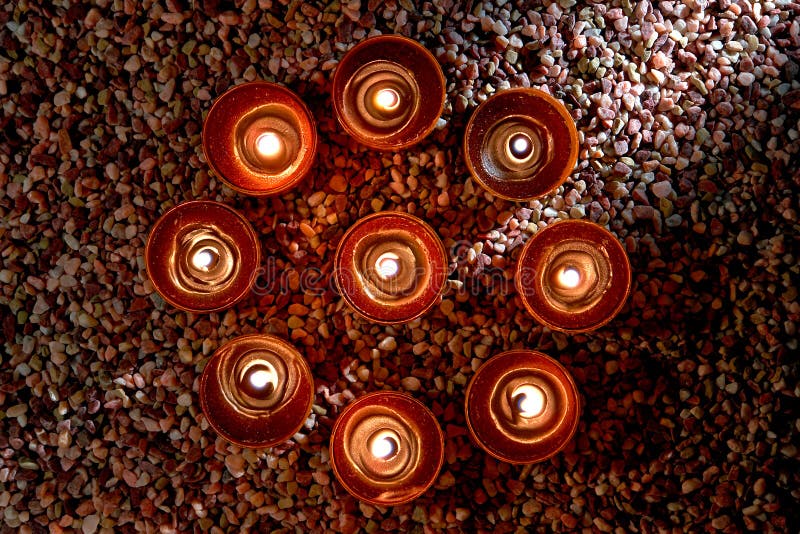 Votive candles burning with a soft glow flame in a symbolic meditation circle wheel over a bed of pea gravel in a spiritual retreat temple. Votive candles burning with a soft glow flame in a symbolic meditation circle wheel over a bed of pea gravel in a spiritual retreat temple