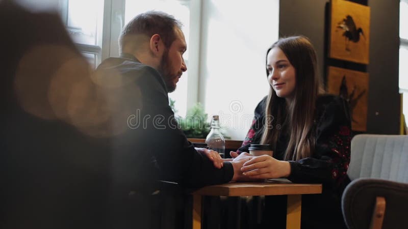 Candid image of young couple in a coffee shop. Caucasian man and woman sitting with a dog in a cafe. Long shot of loft