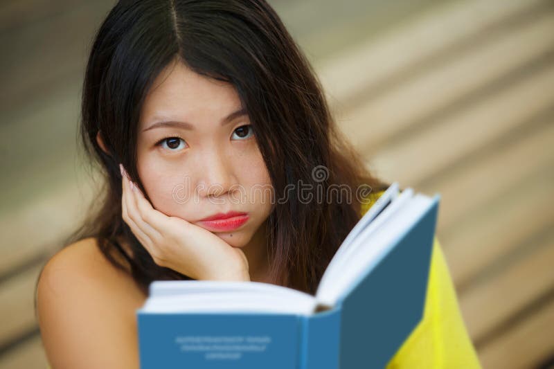 Candid lifestyle portrait of young beautiful and relaxed Asian Korean student girl on reading book or studying outdoors at coffee royalty free stock image Candid lifestyle portrait of young beautiful and relaxed Asian Korean student girl on reading book or studying outdoors at coffee royalty free stock image