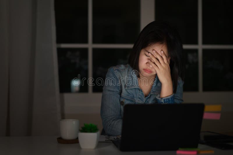 Candid of young asian female student work late night stressed out with project research problem on computer laptop or notebook at
