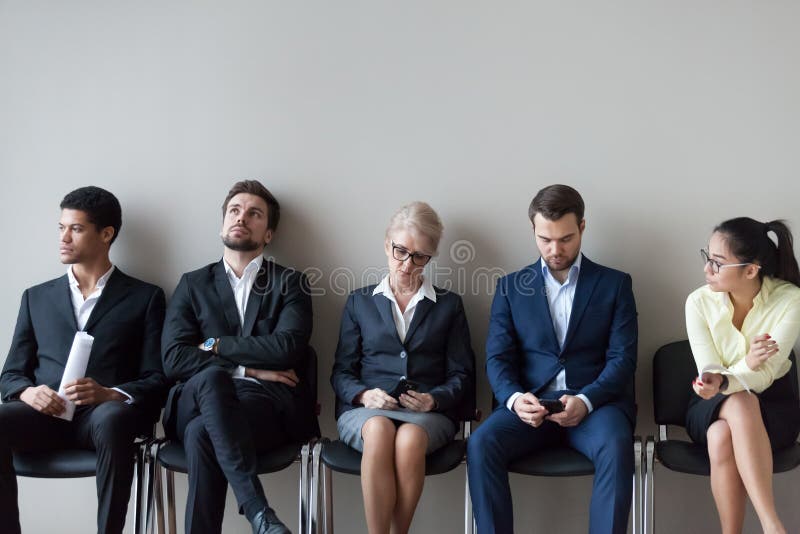 Candidatos de trabalho diversos que sentam a espera na fila pela entrevista