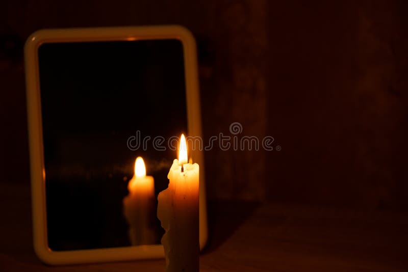 Candle Light in the Reflection of a Mirror Standing on a Table in a