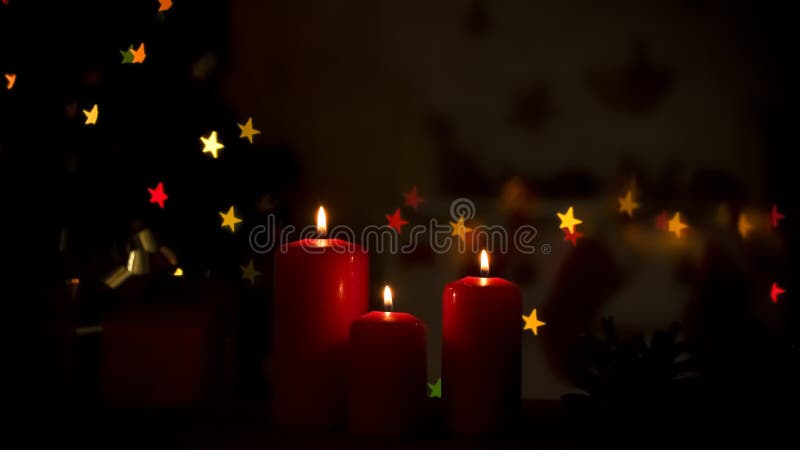 Candles burning near sparkling Christmas decorations, cozy holiday atmosphere