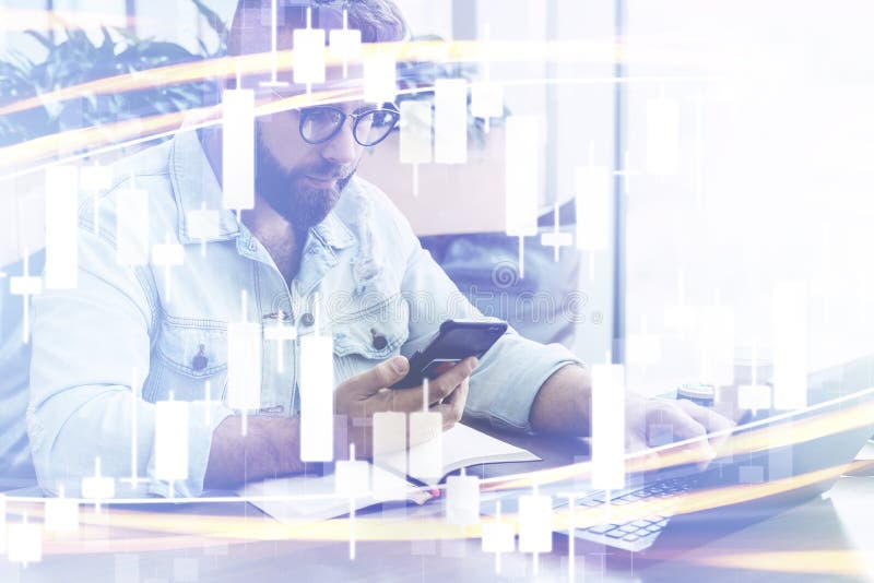 Candlestick chart in foreground. In background man sits, uses smartphone, works on laptop. Businessman reads message in phone royalty free stock image