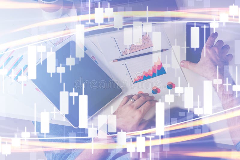 Candlestick chart on foreground. Double exposure. On background man sitting at table, working. On desk is tablet computer, graphs stock images