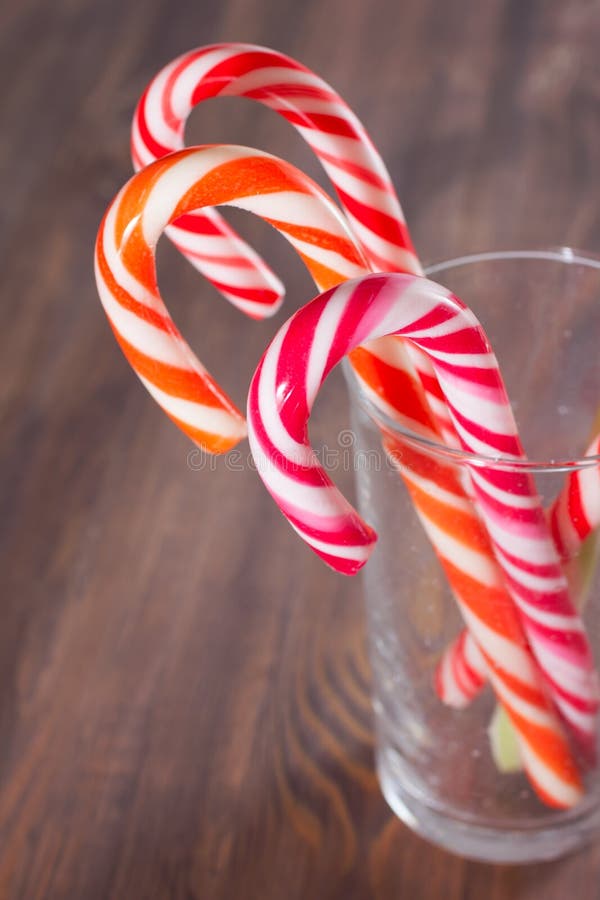 Candy canes in a glass on wooden background