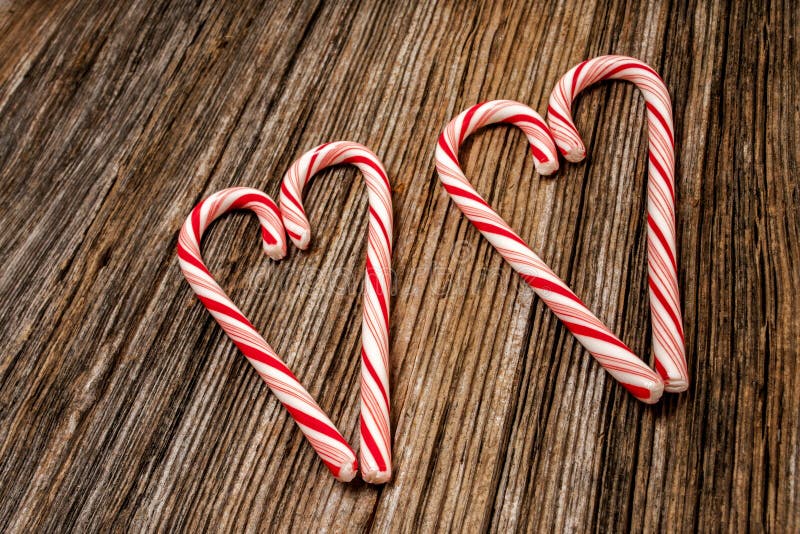 Two seperate candy canes in shape of heart on old barnwood boards. Two seperate candy canes in shape of heart on old barnwood boards