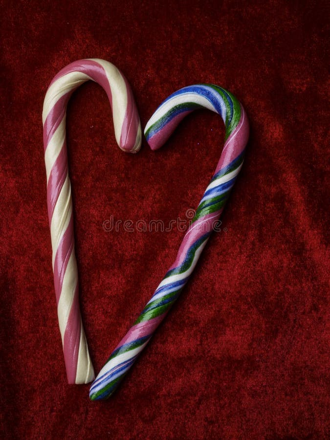 Candy canes making a heart on a red velvet background, Christmas, Weeding or Valentines day greeting card, love concept, copy space, top view