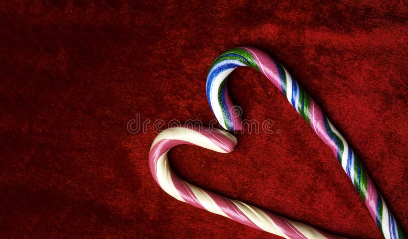 Candy canes making a heart on a red velvet background, Christmas, Weeding or Valentines day greeting card, love concept, copy space, top view