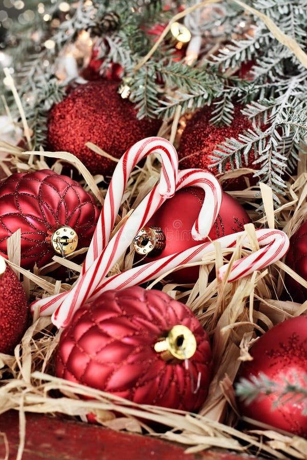 Three candy canes and Christmas ornaments packed in an old antique wooden box with snow covered pine boughs surrounding them. Extreme shallow depth of field with selective focus on center candy. Three candy canes and Christmas ornaments packed in an old antique wooden box with snow covered pine boughs surrounding them. Extreme shallow depth of field with selective focus on center candy.