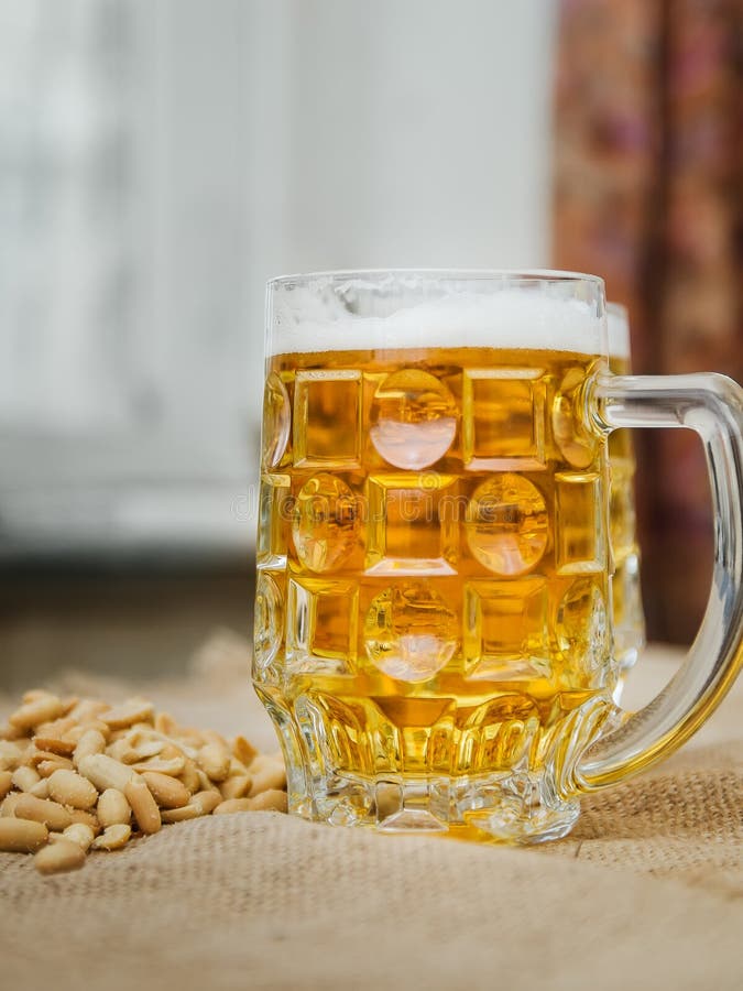 Caneca com cerveja e os amendoins salgados na tabela foto de stock royalty free Caneca com cerveja e os amendoins salgados na tabela foto de stock royalty free