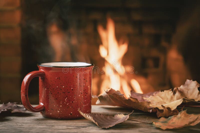 Caneca vermelha com chá quente em frente a uma lareira em chamas, conforto e calor do conceito de coração