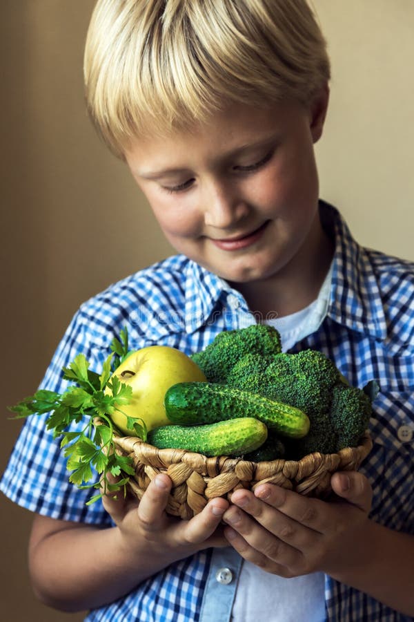 Canestro della tenuta del bambino con le verdure verdi fotografia stock libera da diritti Canestro della tenuta del bambino con le verdure verdi fotografia stock libera da diritti