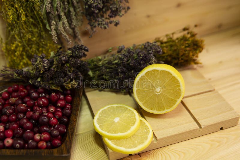 Canneberge rouge, bol de bois, citron jaune coupé, herbe médicinale photographie stock libre de droits