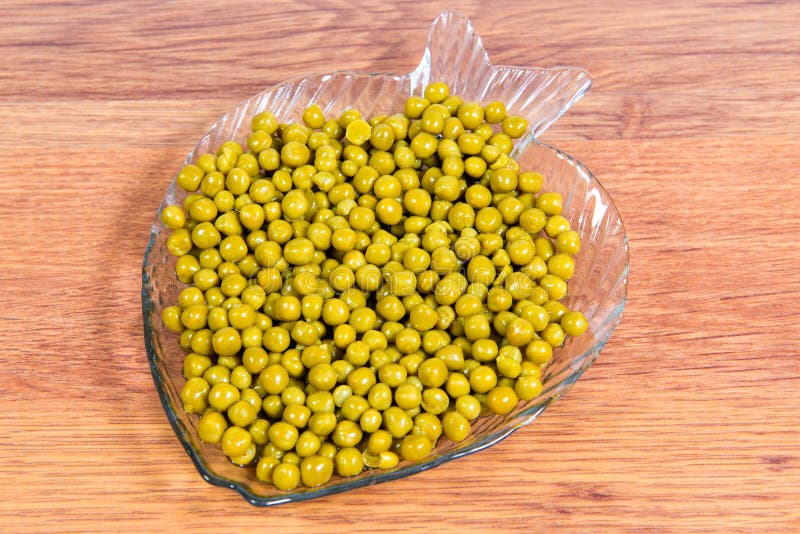 Canned Green Peas in a Glass Plate in the Form of Fish Closeup on the Table. Stock Image