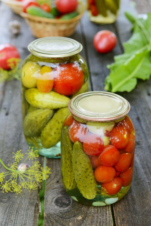Canned tomatoes, cucumbers and garlic in glass jar stock photography