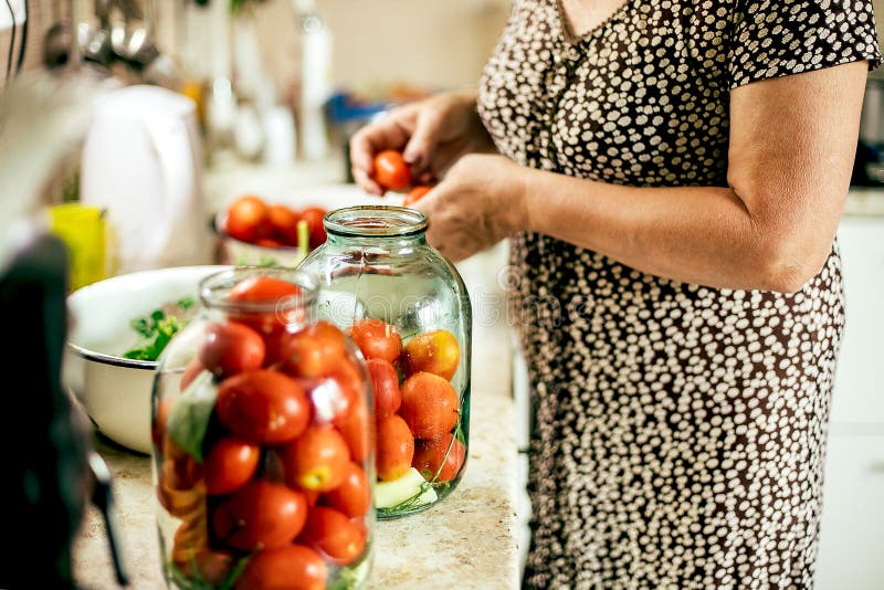 Canning vegetables tomatoes. Woman pickled preserving tomatoes herbs for canning pickling