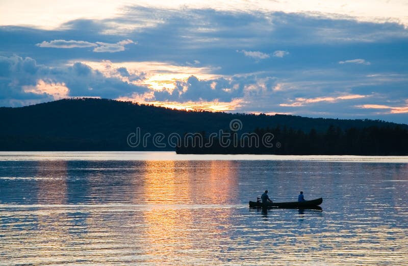 Un paio per un tramonto romantico viaggio in canoa attraverso Moosehead Lago, nel Maine, in una calda sera d'estate.