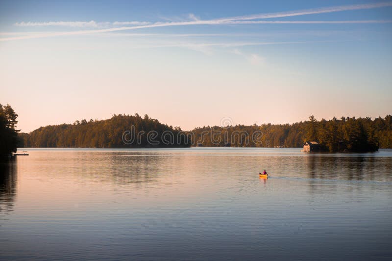 Canoe sul lago tranquillo Joseph, Muskoka, all'alba fotografia stock Canoe sul lago tranquillo Joseph, Muskoka, all'alba fotografia stock