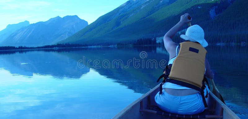 Woman canoing at dusk on a mountain lake. Woman canoing at dusk on a mountain lake