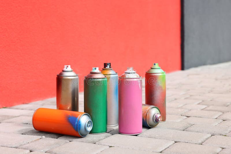 Cans of Different Spray Paints on Pavement Near Wall Stock Image