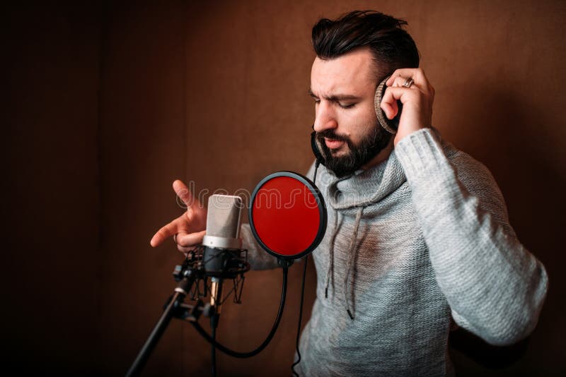 Cantante de sexo masculino que registra una canción en estudio de la música imagenes de archivo Cantante de sexo masculino que registra una canción en estudio de la música imagenes de archivo