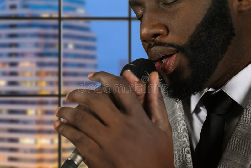 Afro singer with eyes closed. Bearded vocalist on evening background. Concentration and skill. Gentleman's impressive baritone. Afro singer with eyes closed. Bearded vocalist on evening background. Concentration and skill. Gentleman's impressive baritone.