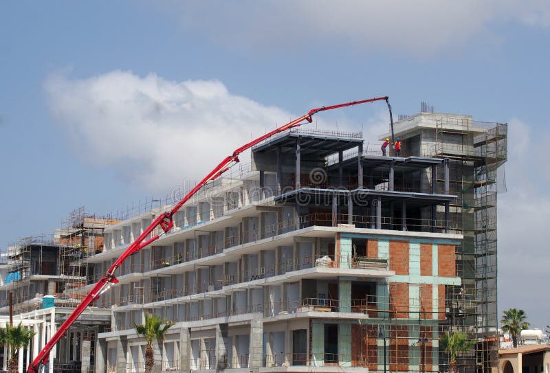 Canteiro de obras com um grande guindaste telescópico vermelho e os trabalhadores da construção que constroem um grande complexo fotografia de stock Canteiro de obras com um grande guindaste telescópico vermelho e os trabalhadores da construção que constroem um grande complexo fotografia de stock